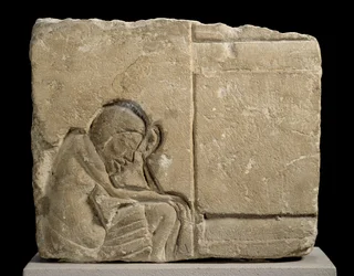 Fragment de calcaire sculpté en relief en creux représentant un serviteur endormi dans le palais